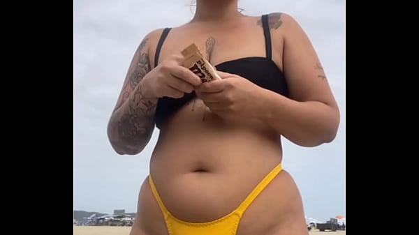 USANDO UM BIQUINI AMARELO BEM APERTADO RACHANDO A BUCETA PRA CHAMAR ATENÇÃO NA PRAIA